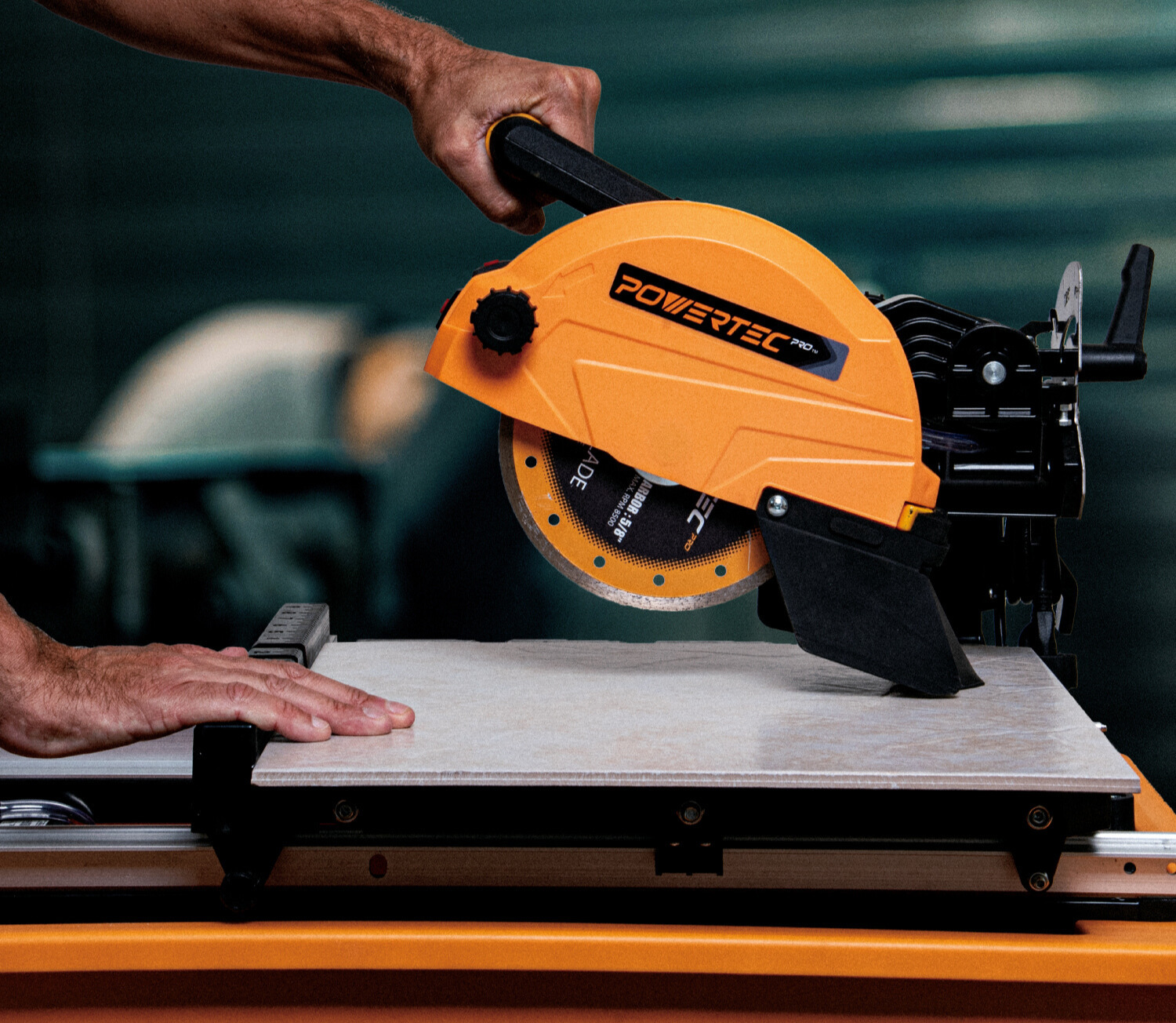 A man wearing a safety mask and goggles operates a Powertec tile saw to cut a ceramic tile, with the stand visible below.