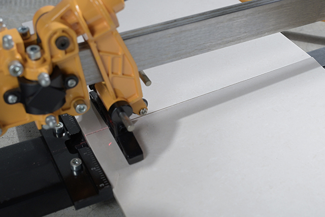 large-format tile cutter scoring a porcelain slab on a stable workbench
